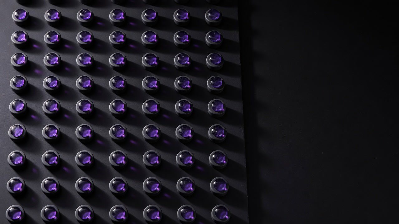 A dark field of steel studs, each tipped with a violet point of light
